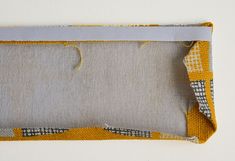 a piece of fabric with yellow and white squares on it, next to a hole in the fabric