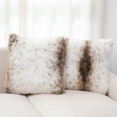 two pillows sitting on top of a white couch