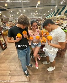 three people are standing in a store and one is holding oranges while the other looks at them