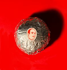 a piece of tin foil sitting on top of a red surface with a man's face