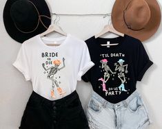 two t - shirts hanging up against a wall with hats on it and one is wearing shorts