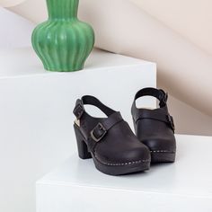 The Astrid slingback clog in black is sure to be one of our most popular styles this season - beautifully detailed with side cut-outs and patinated buckles over the instep and behind the heel. It has the form of a traditional clog, but the crossover strap and double buckles bring it bang up to date. Handcrafted in Italy from the softest black leather, the cushioned sole flexes as you walk for the all-day comfort you'd expect from a Calou clog. Flexible sole with woodlike effect Heel 7,5 cm /2,95 High Heel Clogs, Swedish Clogs, Clogs And Mules, Heel Grips, Clog Boots, Shoes Too Big, Wooden Clogs, Shoe Tree, Clogs Shoes