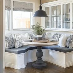 a table with some pillows on it and a bench in front of the window seat