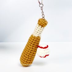 a crocheted keychain with a red and white ball hanging from it