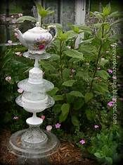 three tiered glass vases sitting on top of each other in front of flowers