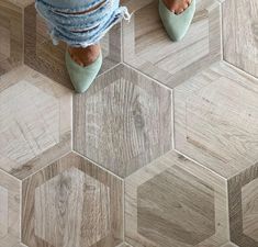 a woman standing on top of a wooden floor next to a tile floor with hexagonal tiles