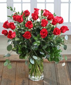 a vase filled with red roses on top of a wooden table