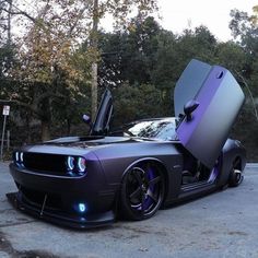 a purple car with its doors open and the hood up on it's side