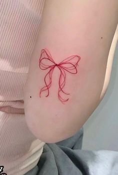 a woman with a red bow tattoo on her arm