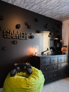 a bedroom with a green bean bag chair and game controller on the dresser next to it