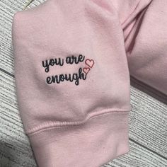 a pink sweatshirt with the words you are enough embroidered on it