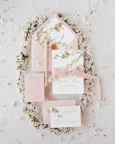 the wedding stationery is laid out on top of flowers