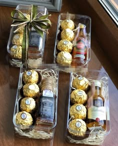 four clear boxes filled with different types of chocolates and bottles of wine sitting on a table