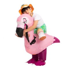 a young boy is hugging an inflatable pink flamingo