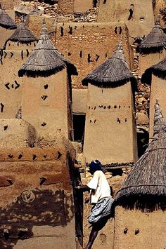 a man climbing up the side of a building with thatched roof tops on it