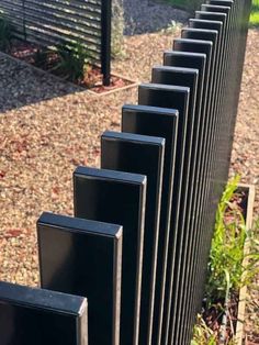 a row of black speakers sitting next to each other on top of a gravel field