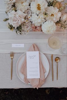 a place setting with flowers and goldware