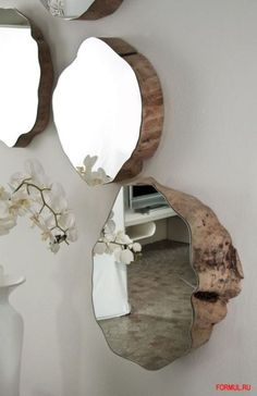 three mirrors are hanging on the wall near a vase with flowers and a white vase