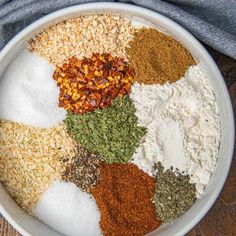 a white bowl filled with different types of spices and seasoning on top of a wooden table