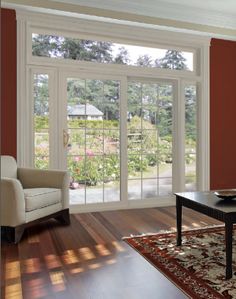 a living room with red walls and white trim on the glass doors that lead out to a garden