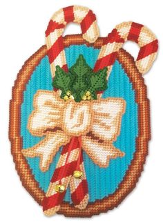 a cross stitch ornament with candy canes and holly on it's bow