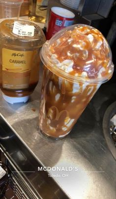 iced coffee with caramel and whipped cream in a plastic cup on a metal counter