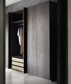 an open closet with clothes hanging on the door and two drawers in front of it