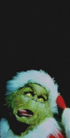 the grinch is wearing a santa hat and holding his hand up to his ear