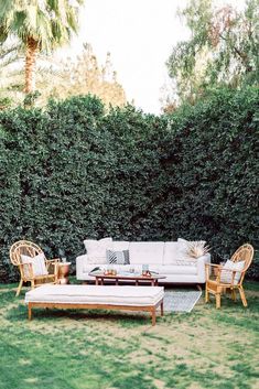 an outdoor living room with wicker furniture and greenery