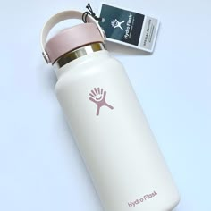 a white water bottle with a pink lid next to a tag on a blue background