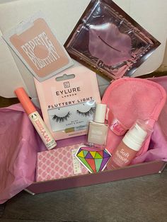 an open pink box containing makeup, eyeliners and other items sitting on the floor