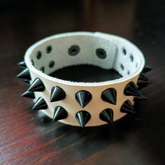 This is a Punk Black Spike & Black/White/Pink/Red Leather Cuff Bracelet. It's a gift for men or women. This will be a perfect gift for your friends. Black, white and pink bracelets are made of cowhide leather. Red bracelets are made of PU leather.(Only PU leather can make the bright red color). This product is handmade and takes 1 day to make. It will be shipped as soon as possible on the next day. This punk bracelet can be customized with a name or simple text in your preferred location. If you Adjustable Punk Cuff Bracelet With Black Band, Adjustable Black Band Punk Cuff Bracelet, Adjustable Punk Bracelet For Streetwear, Adjustable Punk Bracelets For Streetwear, Edgy Band Bracelet For Concerts, Edgy Band Bracelet For Concert, Edgy Bracelet With Black Band As Gift, Edgy Black Band Bracelet For Gift, Edgy Black Band Bracelet As Gift