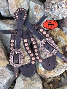 a pair of brown leather boots with metal buckles on them sitting on some rocks