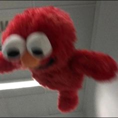 a close up of a red stuffed animal with big eyes and an angry look on it's face