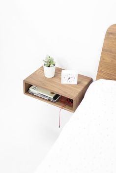 a bed with a wooden headboard and night stand on top of it next to a white wall