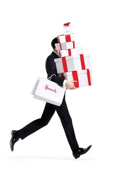 three men in black suits carrying boxes with red and white bows on them, while walking