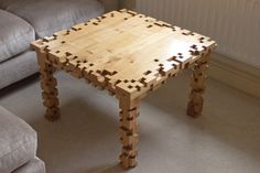 a table made out of wooden blocks sitting on top of a floor next to a couch