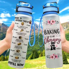 two people holding up their water bottles in front of some mountains and trees with the words baking is my therapy