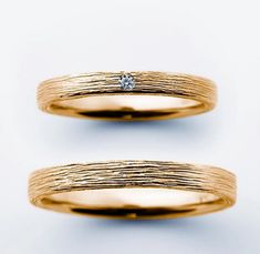 two yellow gold wedding bands with a diamond in the center, on a white background