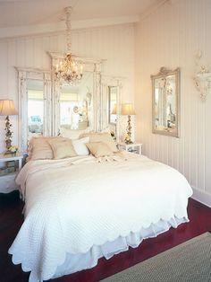 a white bed sitting in a bedroom on top of a hard wood floor next to two lamps