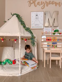 a little boy reading a book in his playroom with a tent on the floor