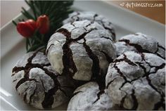 some cookies are on a white plate with red flowers and greenery in the background