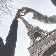 two people holding their hands up to the eiffel tower in paris, france