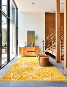 a yellow area rug in the middle of a room with stairs and wooden furniture on either side