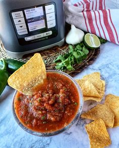 a bowl of salsa with tortilla chips and an instant pot in the background