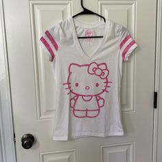 White T-Shirt With Hello Kitty On Front In Pink. 2 Stripes Around Cap Sleeves In Matching Pink. V Neck. Somewhat Fitted In Body Of Shirt But Not Clingy. Size Xs. Never Worn. No Tags White Hello Kitty Casual Tops, White Casual Hello Kitty Tops, White Cotton Hello Kitty Top, Casual White Hello Kitty Top, White Hello Kitty Trendy Tops, White Trendy Hello Kitty Tops, White Short Sleeve Hello Kitty T-shirt, White Hello Kitty Cotton T-shirt, White Cotton Hello Kitty T-shirt