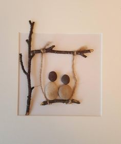 two rocks sitting on top of a branch in the shape of a frame with branches