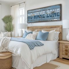 a bed with white sheets and blue pillows in a bedroom next to a basket on the floor