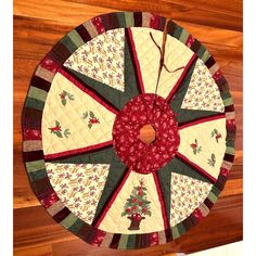 a quilted christmas ornament hanging on a wooden wall with red and green trim