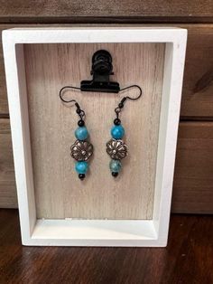 Introducing our exquisite handmade Boho Hippie Southwest Style Dangle Earrings, crafted with a vibrant blend of turquoise-dyed beads and sleek black glass beads. These charming earrings feature a stunning antique silver main focal point, beautifully shaped like a delicate flower. Perfect for adding a touch of rustic elegance to any outfit, these earrings embody a free-spirited, earthy aesthetic that is both timeless and unique. Embrace your inner bohemian with these one-of-a-kind statement pieces that effortlessly combine vintage charm with modern style. Turquoise Beaded Earrings With Black Beads As Gift, Turquoise Earrings With Black Round Beads, Earthy Aesthetic, Southwest Style, Kansas City Mo, Beaded Dangle Earrings, Free Spirited, Handmade Boho, Delicate Flower